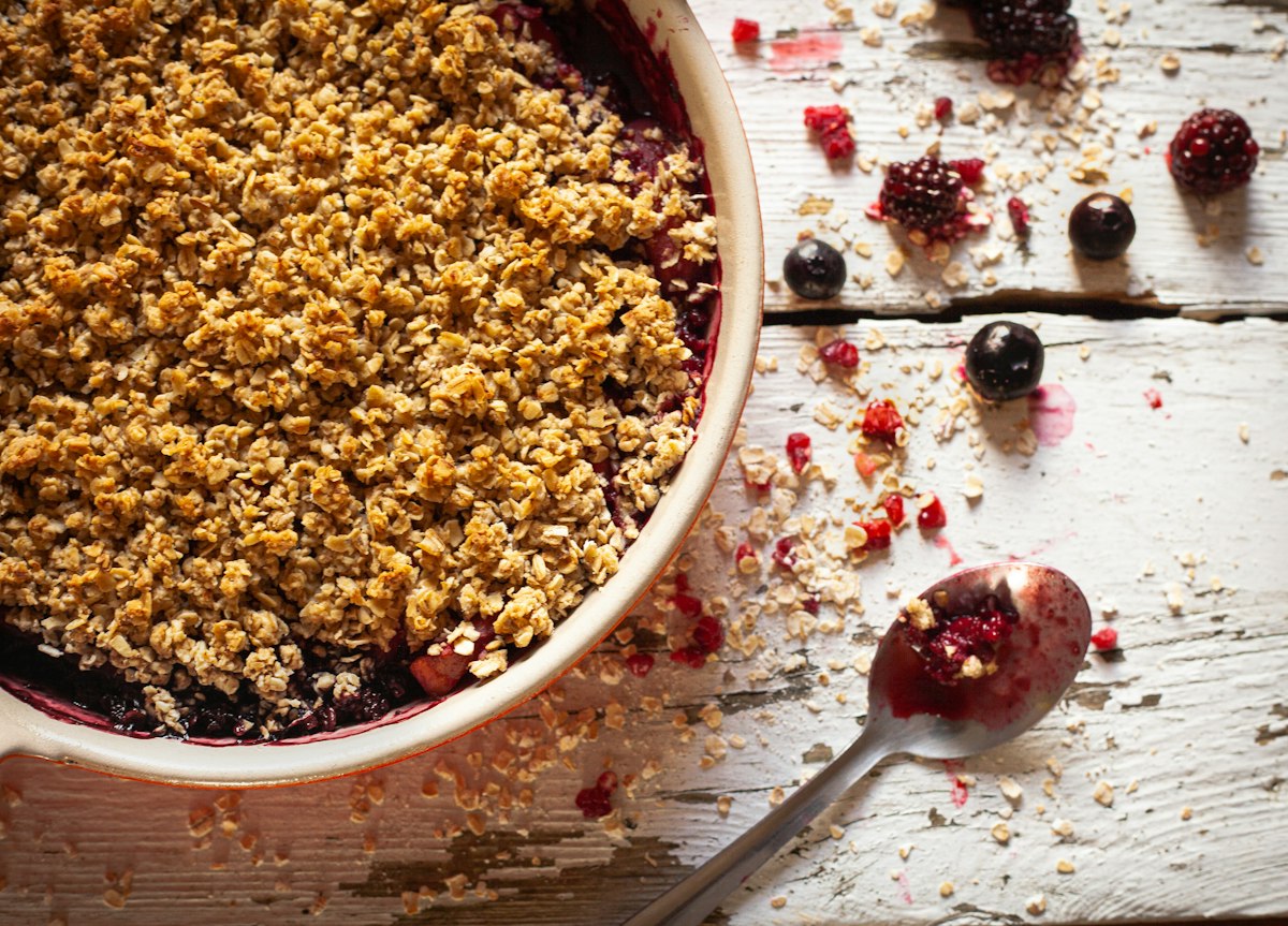 A berry crumble with a thick golden oat topping in a baking dish