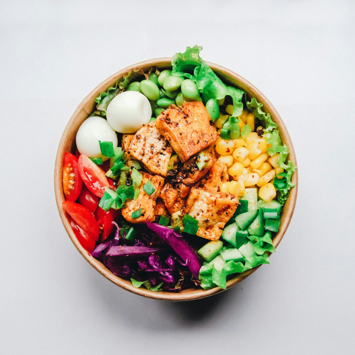 A bowl of tofu, edamame, corn and crisp raw vegetables