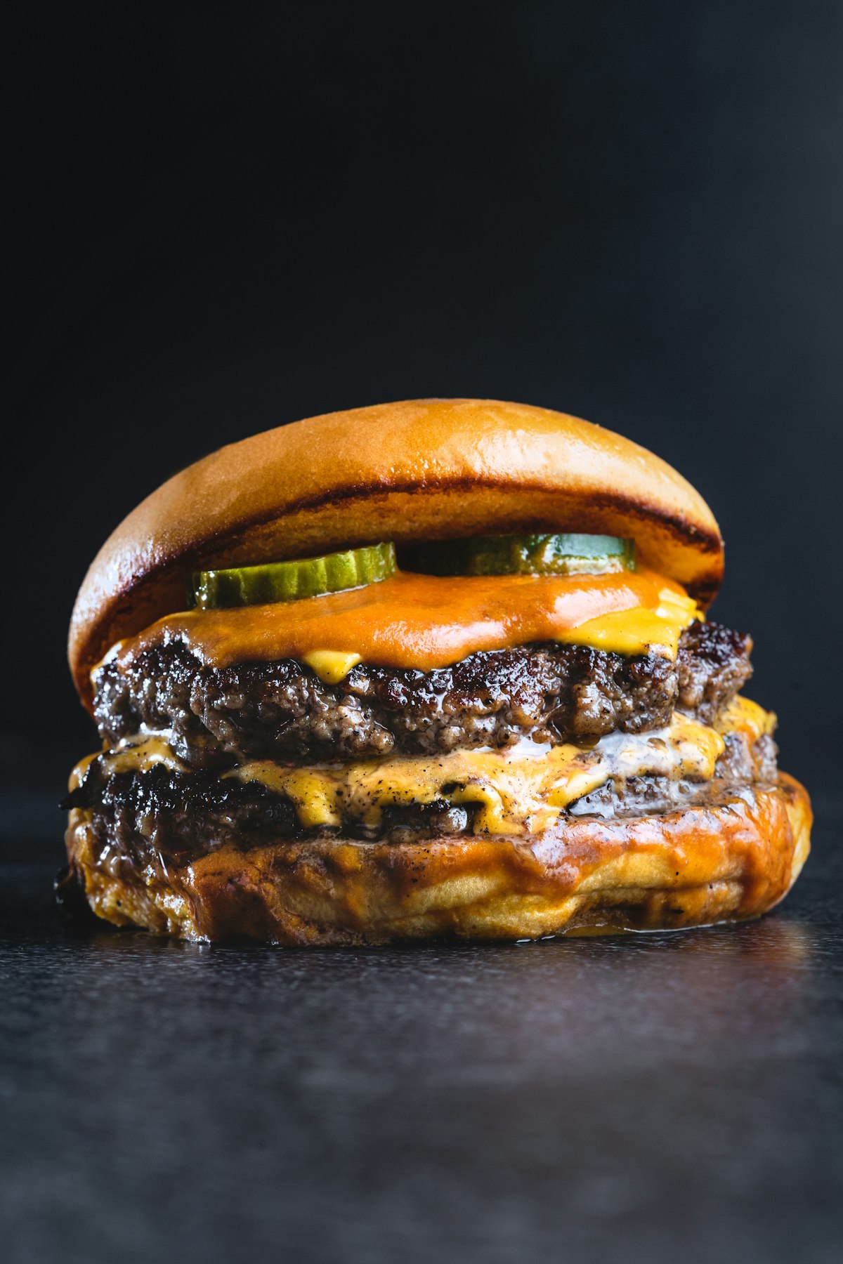 A double smash burger with melted cheese and pickles in a toasted bun
