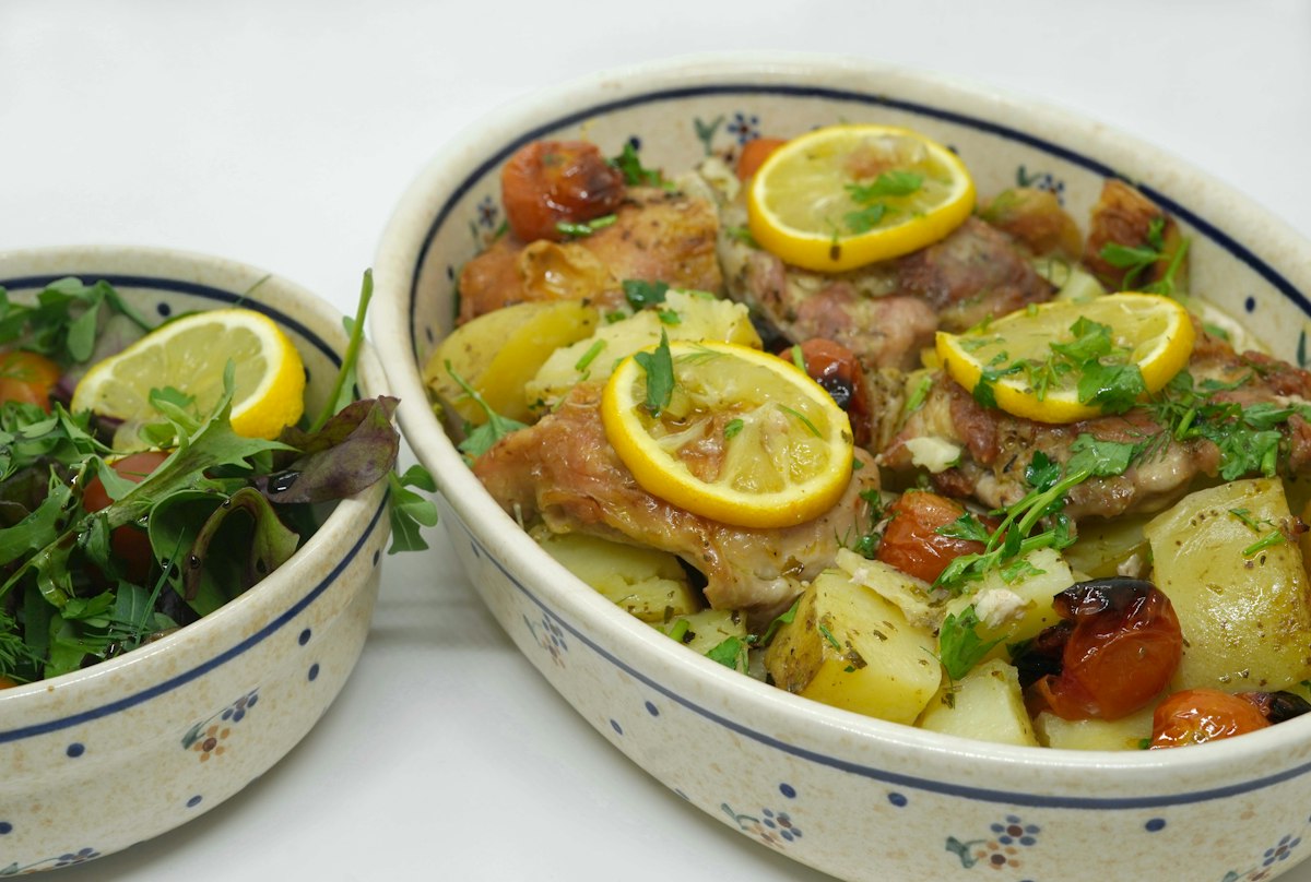 Chicken tajine with lemon slices, herbs and potatoes in a ceramic dish