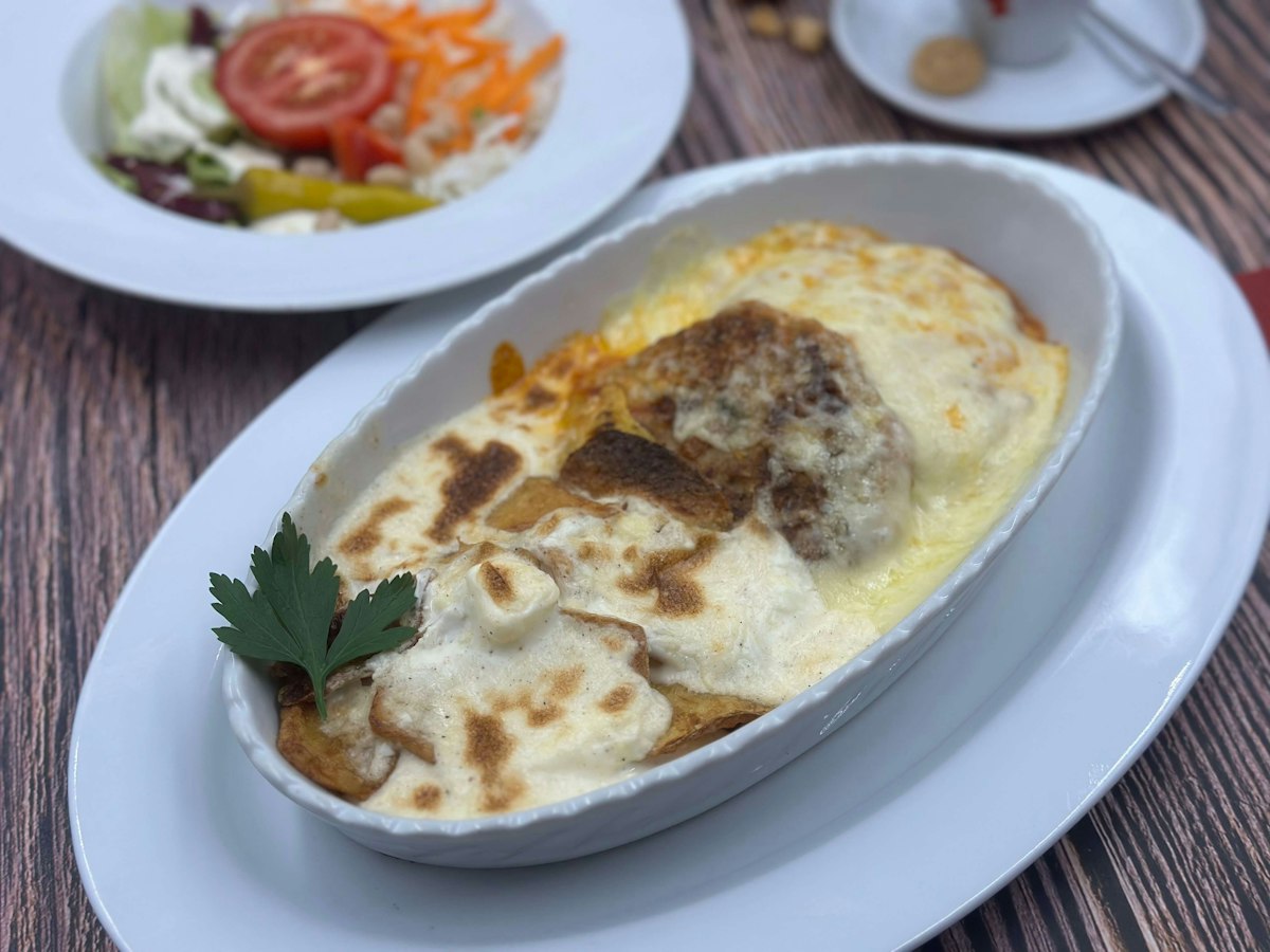 A baked moussaka with a golden bechamel top in an oval dish