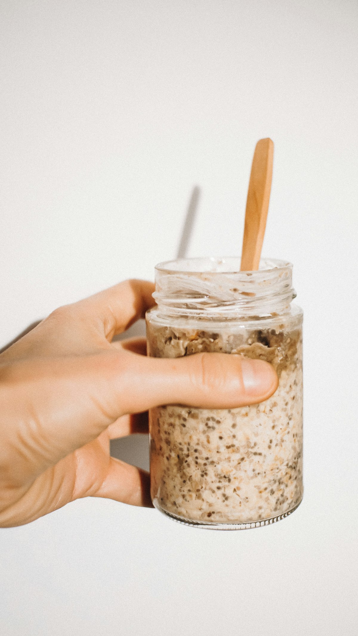 A jar of creamy overnight oats with a wooden spoon