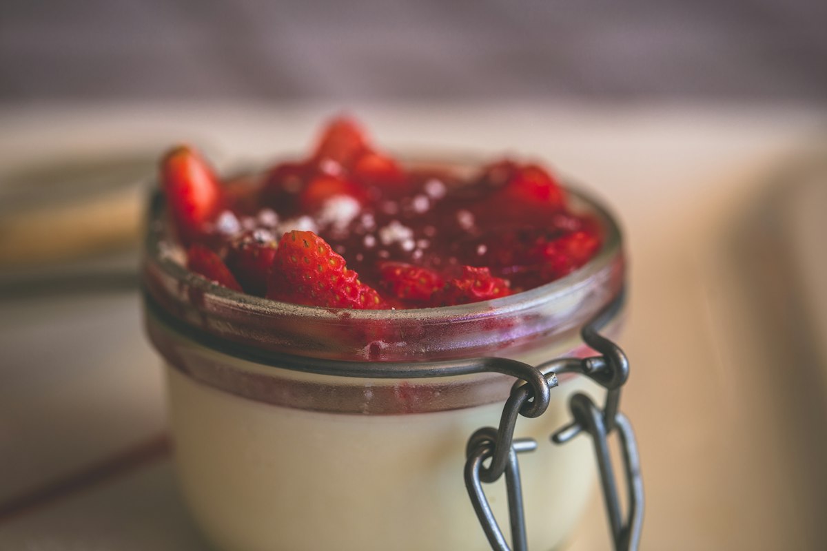 A jar of set panna cotta topped with strawberry compote