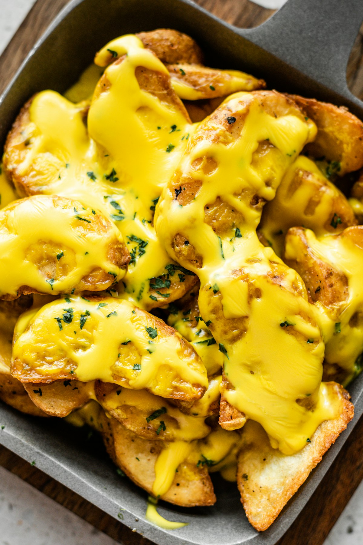 Golden potatoes smothered in melted raclette cheese in a pan