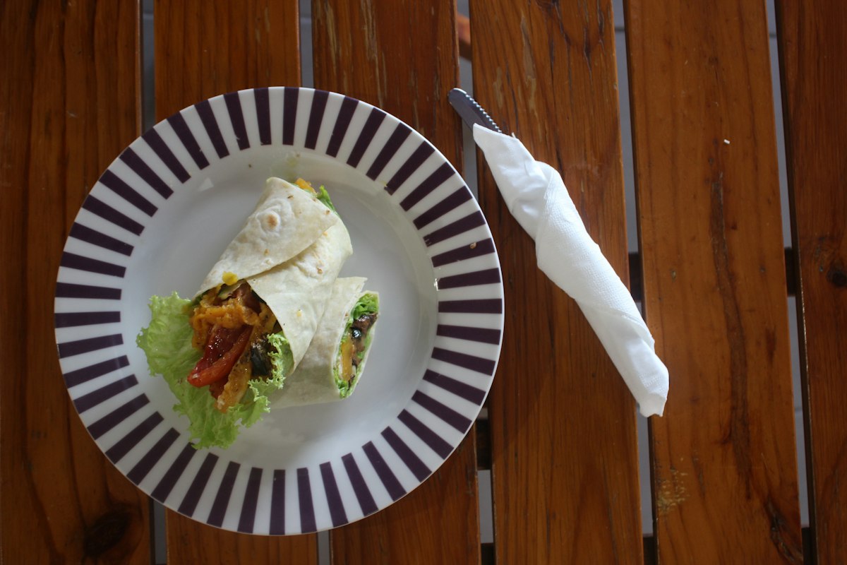 A vegetable wrap cut and plated with lettuce and roasted peppers