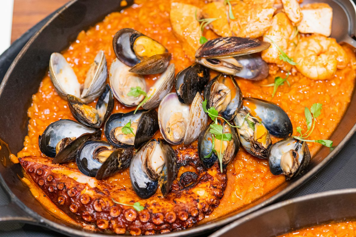 A pan of seafood paella with mussels, prawns and octopus on saffron rice