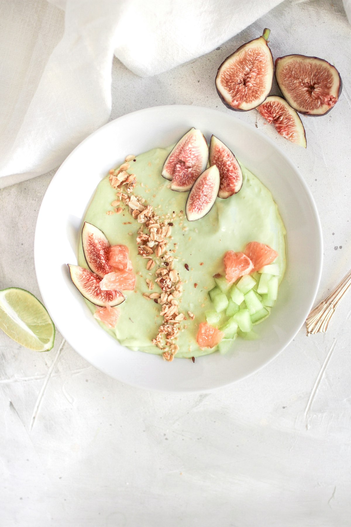 A green smoothie bowl topped with figs, granola and citrus