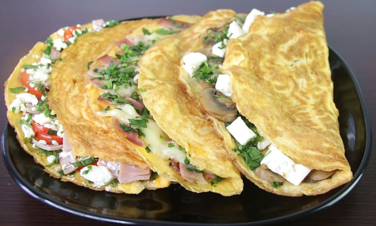 Folded omelettes filled with feta and fresh herbs on a dark plate