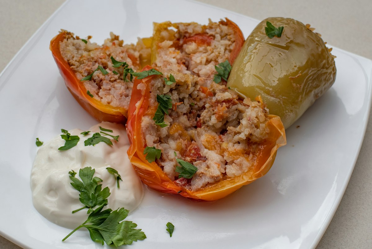 Halved bell peppers stuffed with herby rice and served with a spoon of yogurt