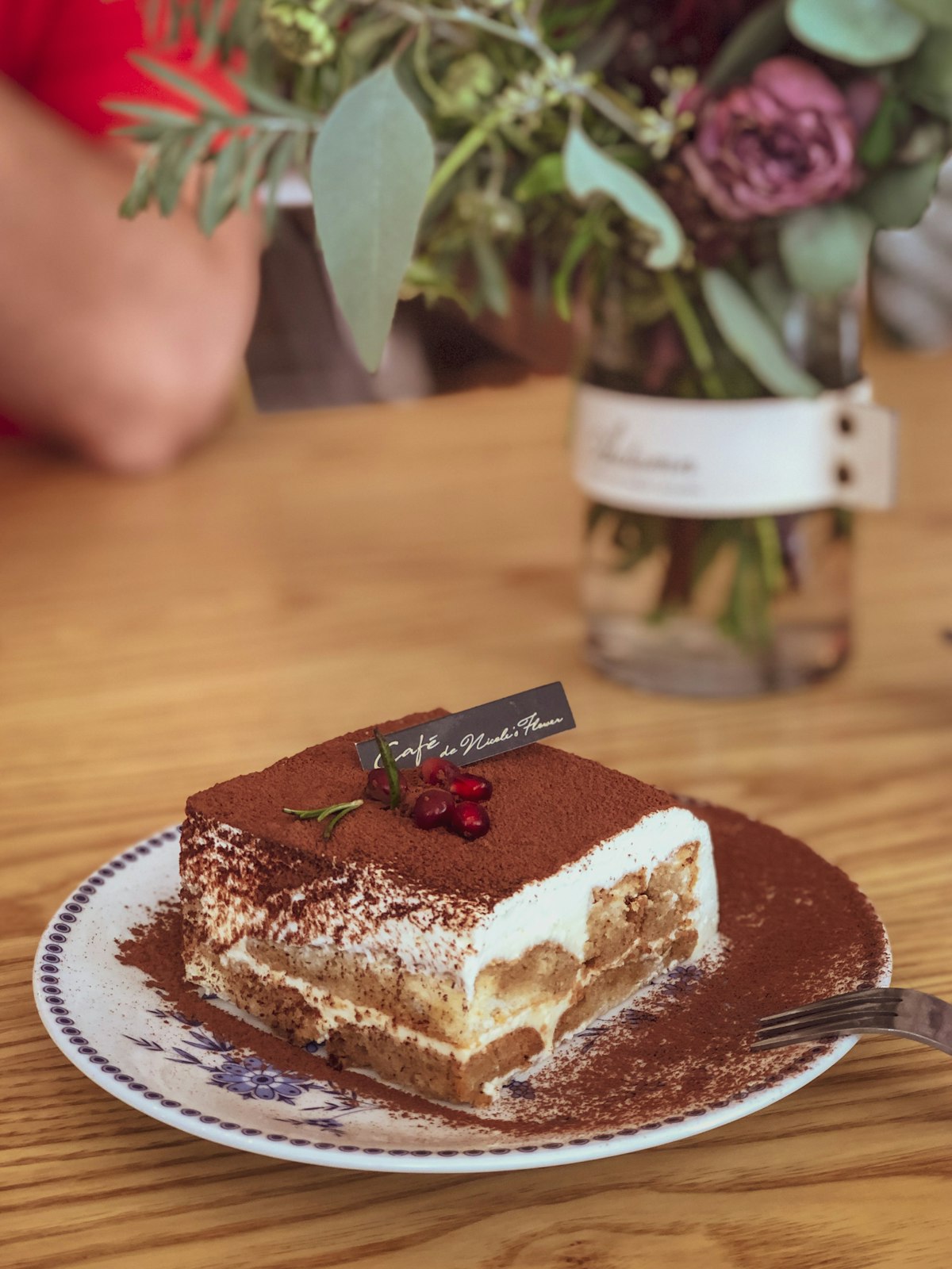 A slice of tiramisu dusted with cocoa showing its cream and sponge layers